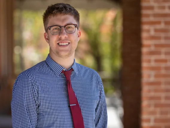 Dan Kellish smiling for photo, wearing blue button up shirt and red tie