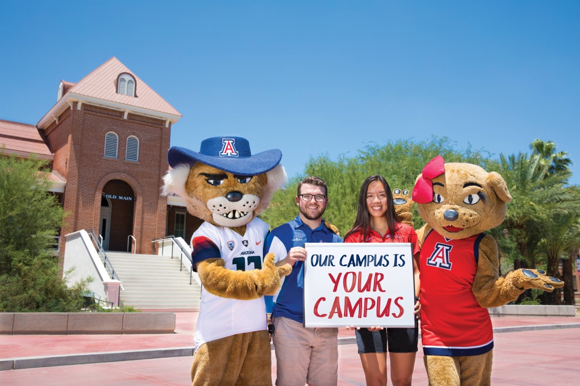 Wilbur, Wilma, and two University employees holding sign that reads "Our campus is your campus"