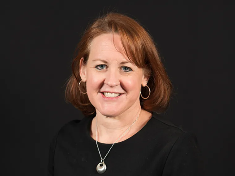 Emily McCarthy smiling for photo, wearing black blouse and silver necklace