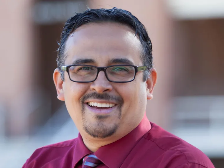 Rudy McCormick smiling for photo, wearing maroon collared shirt and stripped tie