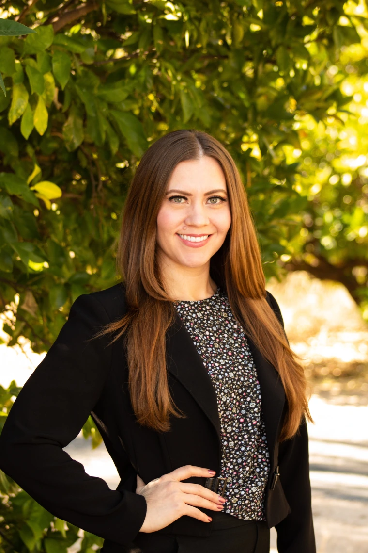 Headshot of Danielle Crosby smiling directly at camera while standing in front of a tree